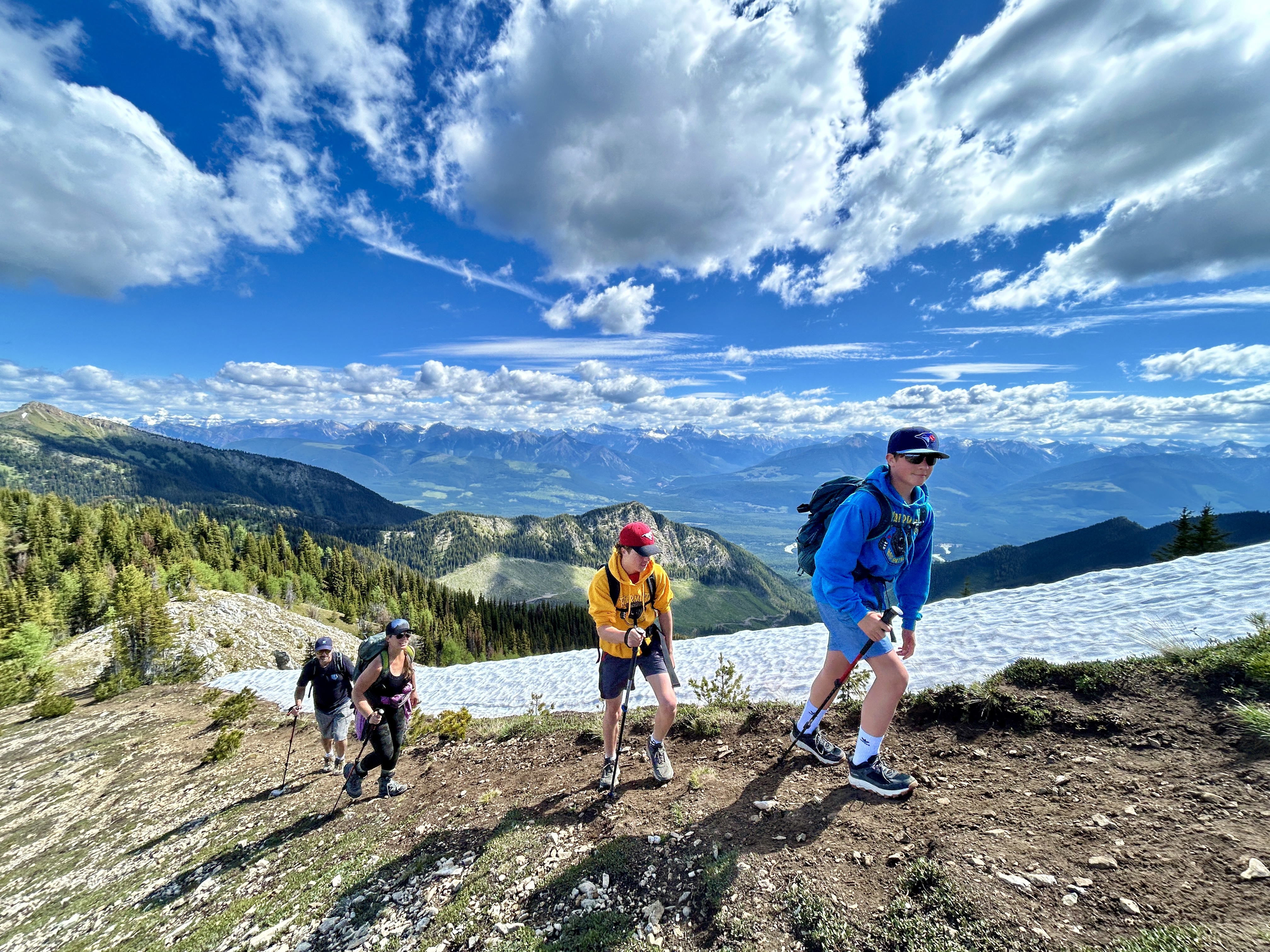 Group of hikers ascending a ridge with mountain panorama